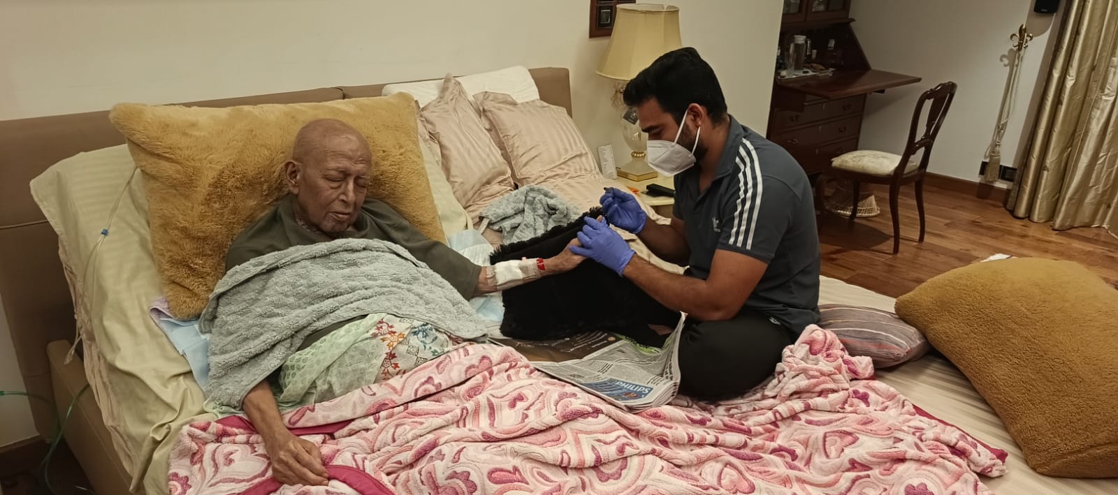 Caregiver giving medical assistance to patient in bed